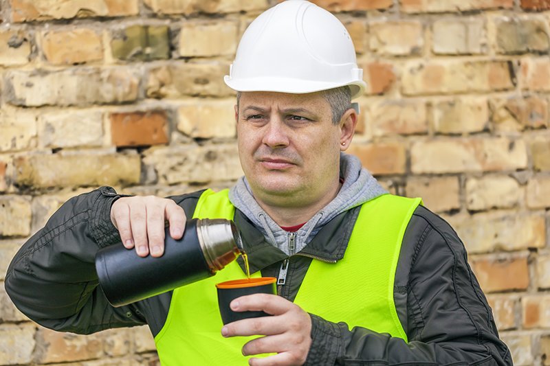 Builder pouring hot drink on site
